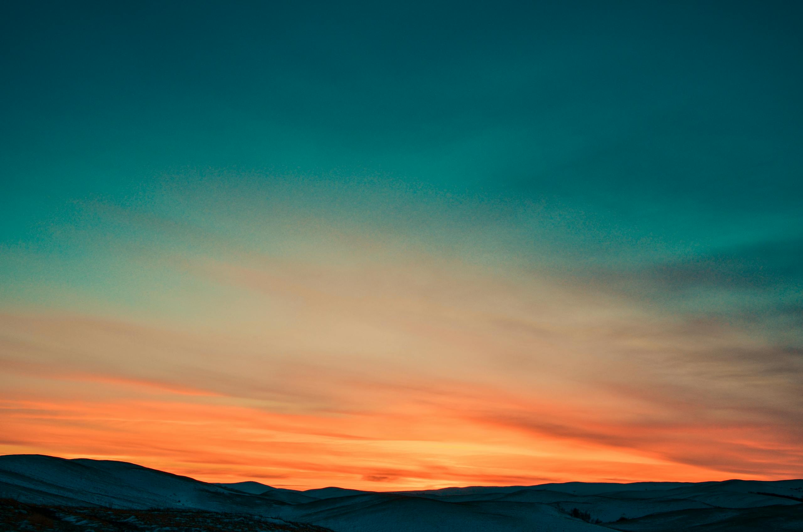 Capture of a stunning twilight sky with colorful gradients over gentle hills.